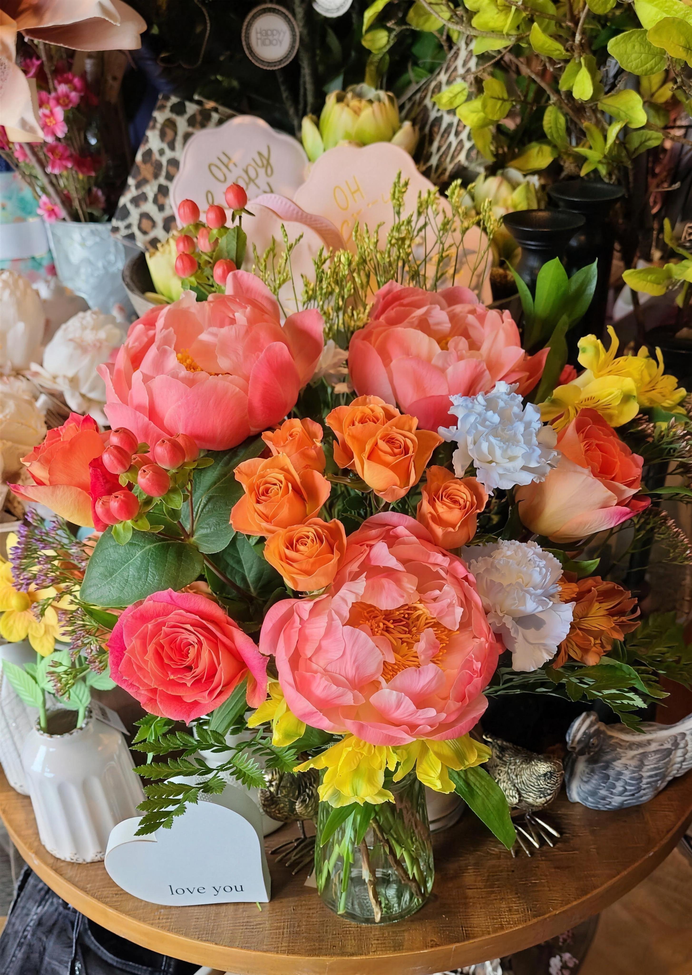 A signature Petal Express arrangement of coral peonies, roses, and mixed blooms